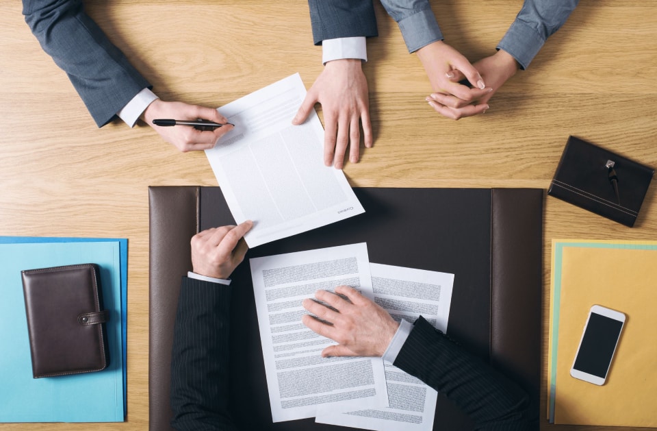 Business contract being signed across a conference table