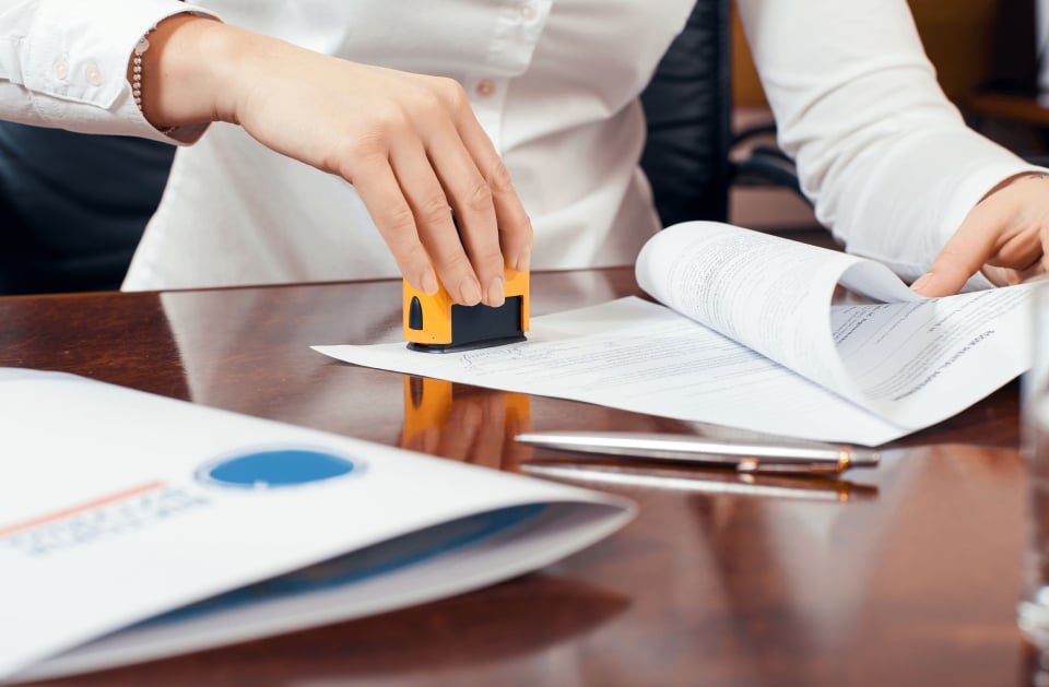Notary stamping a document at a polished desk