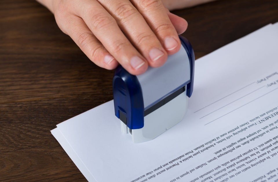Close-up of signed documents and a notary stamp resting on a desk