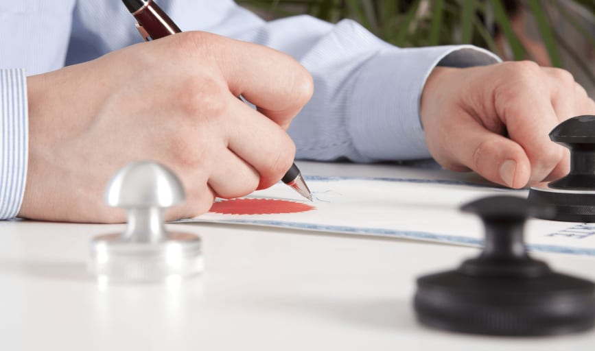Signing a certificate bearing a red embossed notary seal